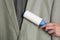 Woman cleaning light grey jacket with lint roller