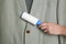 Woman cleaning light grey jacket with lint roller