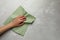 Woman cleaning light grey table with paper towel, top view. Space for text