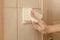 Woman cleaning light switch with napkin, closeup