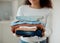 Woman cleaning a pile of laundry. Woman holding a stack of neat, folded clothing. Hands of a woman doing housework