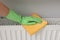 Woman cleaning radiator with rag indoors, closeup