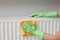 Woman cleaning radiator with rag indoors, closeup