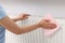 Woman cleaning radiator with rag indoors, closeup