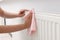 Woman cleaning radiator with rag indoors, closeup