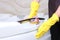 A woman in a cleaning service uniform and rubber gloves wipes the chrome surface.Cleanliness and hygiene in the bathroom