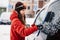 Woman cleaning snow off his car during winter snowfall. Scraping ice. Winter window cleaning.