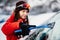 Woman cleaning snow off his car during winter snowfall. Scraping ice. Winter window cleaning