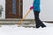 Woman cleaning snow with shovel in winter day. Woman shovelling snow walkway in front of house