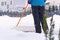 Woman cleaning snow with shovel in winter day. Woman shovelling snow walkway in front of house