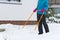 Woman cleaning snow with shovel in winter day. Woman shovelling snow walkway in front of house