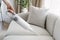 Woman cleaning soft sofa using wireless vacuum