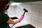 Woman cleaning tiles in the kitchen with steam machine.