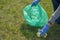 Woman cleaning up nature of garbage. Volunteer hands with blue gloves picking up trash into plastic bag. Volunteering