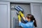 Woman cleaning wall-mounted hood ventilation grill in bathroom with vacuum cleaner