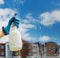 Woman cleaning a window using clean sprayer in action with blue gloves