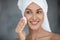 Woman cleans face skin removing makeup uses cotton pad closeup