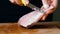Woman cleans fish on a cutting board with a knife, cooking seafood close-up