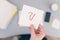 Woman clerk sitting at the office table and holding note sticker with question and exclamation mark.