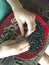 The woman clicks sunflower seeds. On her knees she has a plate with seeds, and she folds the husks.