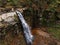 woman on the cliff looking at waterfall enjoying the view