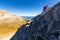 Woman climbing steep mountain slope.