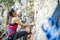 A woman climbing a steep rock in climbing harness