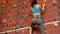 Woman climbing up rock wall