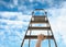 Woman climbing up stepladder against blue sky with clouds, closeup