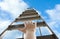 Woman climbing up stepladder against sky with clouds, closeup