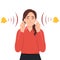 Woman with closed eyes is plugging her ears with fingers when suffering from tinnitus. Red bells as symbol of unbearable ringing