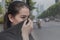 Woman closes her nose with hand because of bad traffic pollution.