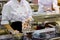 A woman in the clothes of a cook roasts food in a frying pan in the kitchen of a cafe