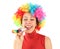 Woman in clown wig and with party blower, laughing