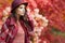 Woman in coat with hat and scarf in autumn park