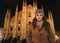 Woman in coat standing in front of Duomo in evening, Milan