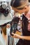 Woman cobbler working on machine in her shoemaker workshop