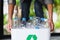 A woman collecting and holding recyclable garbage plastic bottles in a trash bin