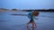 Woman collecting seashells on the beach and abandoned old pier or bridge.