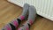 Woman in colorful socks keeping cold feet near heating radiator