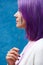 Woman with colourfull purple hair, turn her profile with lavender stem in hand