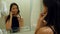 Woman combing her hair, preen and talking with her friend via smartphone in a hotel bathroom