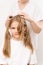 woman combs and does the hair of a kid girl on a white background.