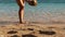 Woman coming up to whole coconut beverage to take it for drink and run away on a whote sand beach with azure ocean water