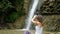 Woman communicates in headphones via video call on a smartphone in nature on the background of a large waterfall, shows