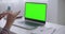 Woman is communicating online by video chat on laptop with green screen for chroma key technology, closeup view on table