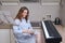 Woman composer in a nightgown writes sheet music on a piece of paper. Writing music at home with a digital piano