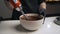 Woman confectioner in black uniform prepare cream for chocolate mousse cake. Stage cooking mousse cake