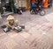 Woman in conical hat sitting on low stool on city pavement checking and selling eggs for a living in Saigon, Ho Chi Min City