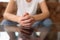 Woman with connected hands sitting on couch close up.